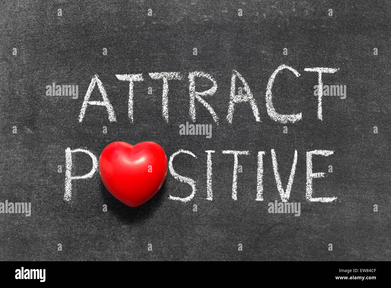 attract positive phrase handwritten on blackboard with heart symbol instead of O Stock Photo