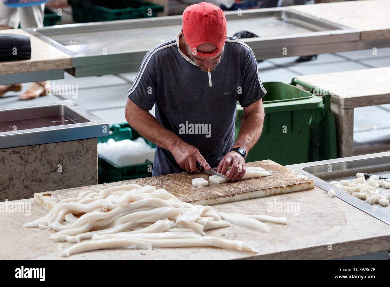 Man smoking while cleaning black scabbardfish, is a bathypelagic in Mercado dos Lavradores, the fish market in Funchal Madeira Stock Photo