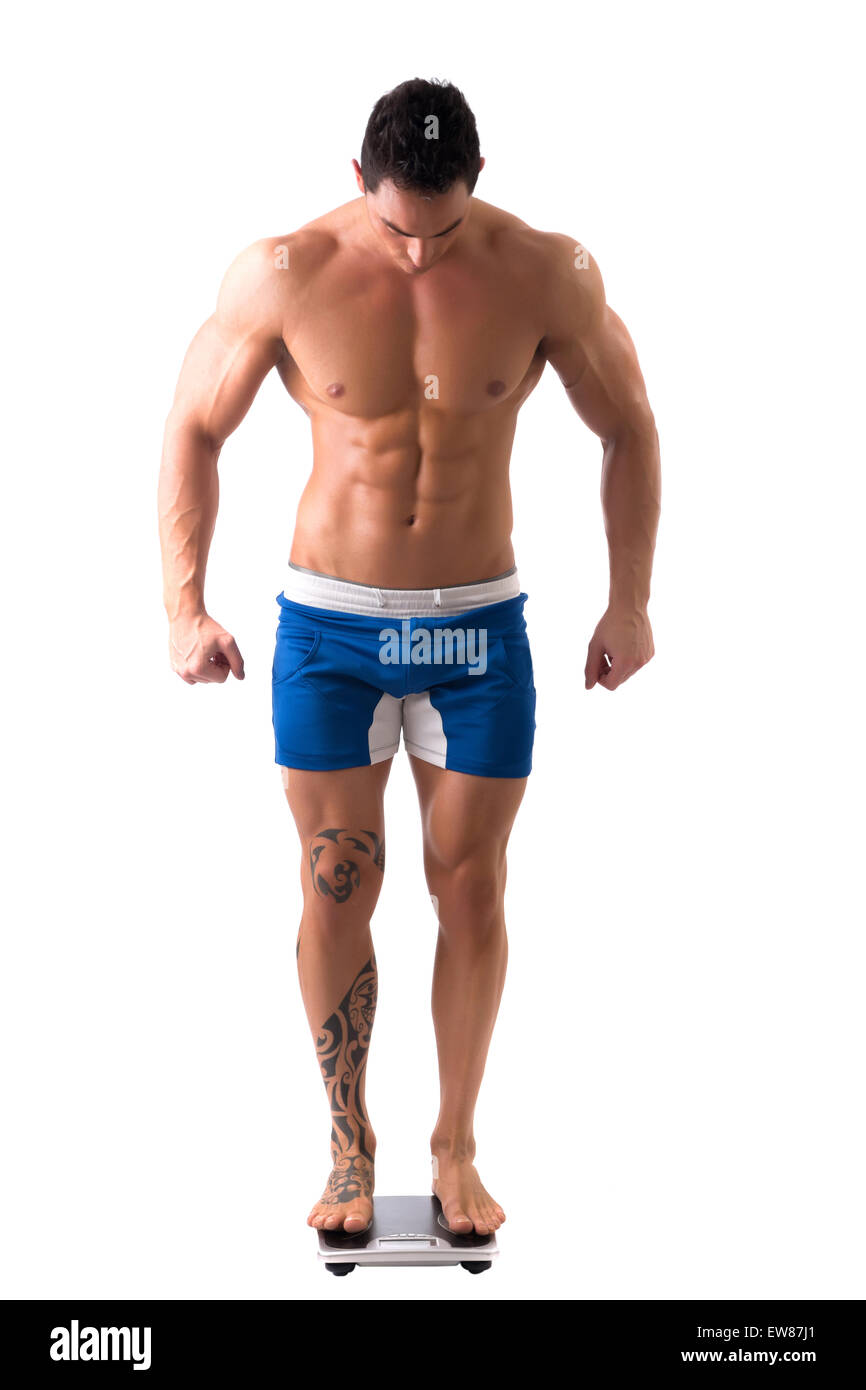 Muscular young man weighing himself on scale, making OK sign with thumb ...