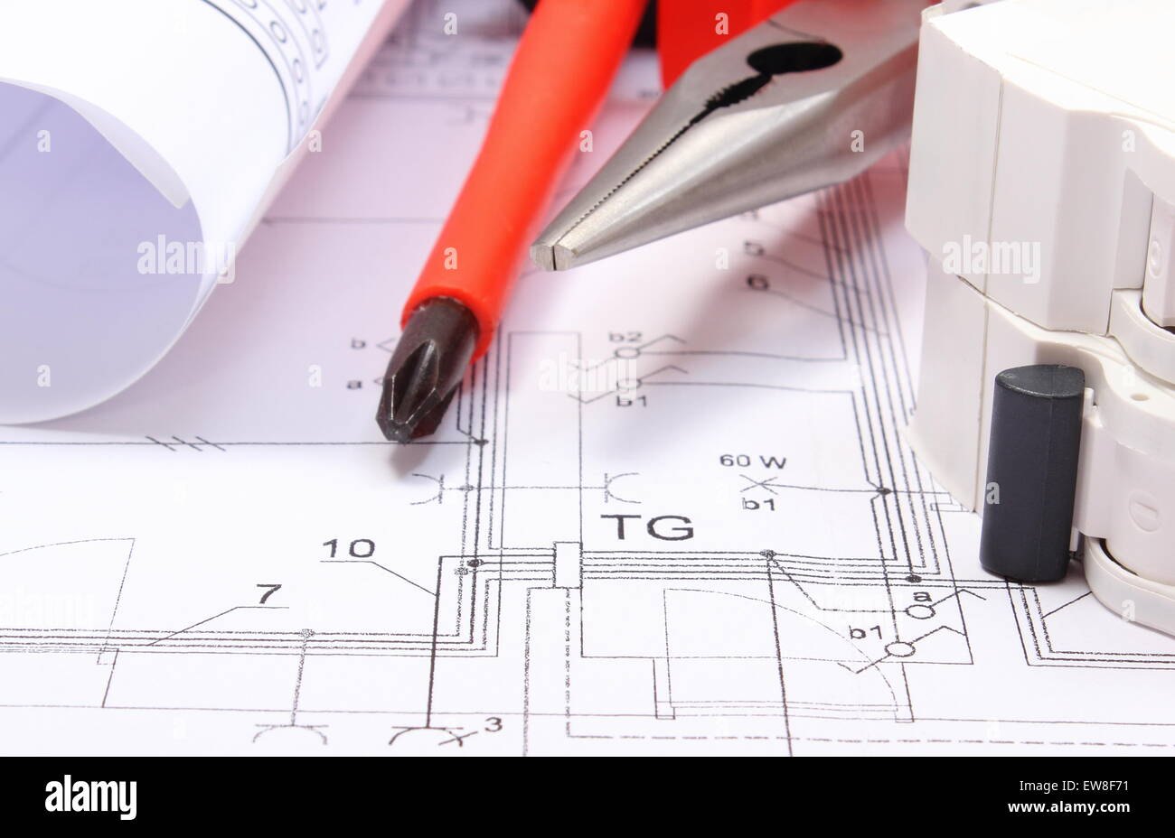 Rolls of electrical diagrams, electric fuse and work tools lying on construction drawing of house, Stock Photo