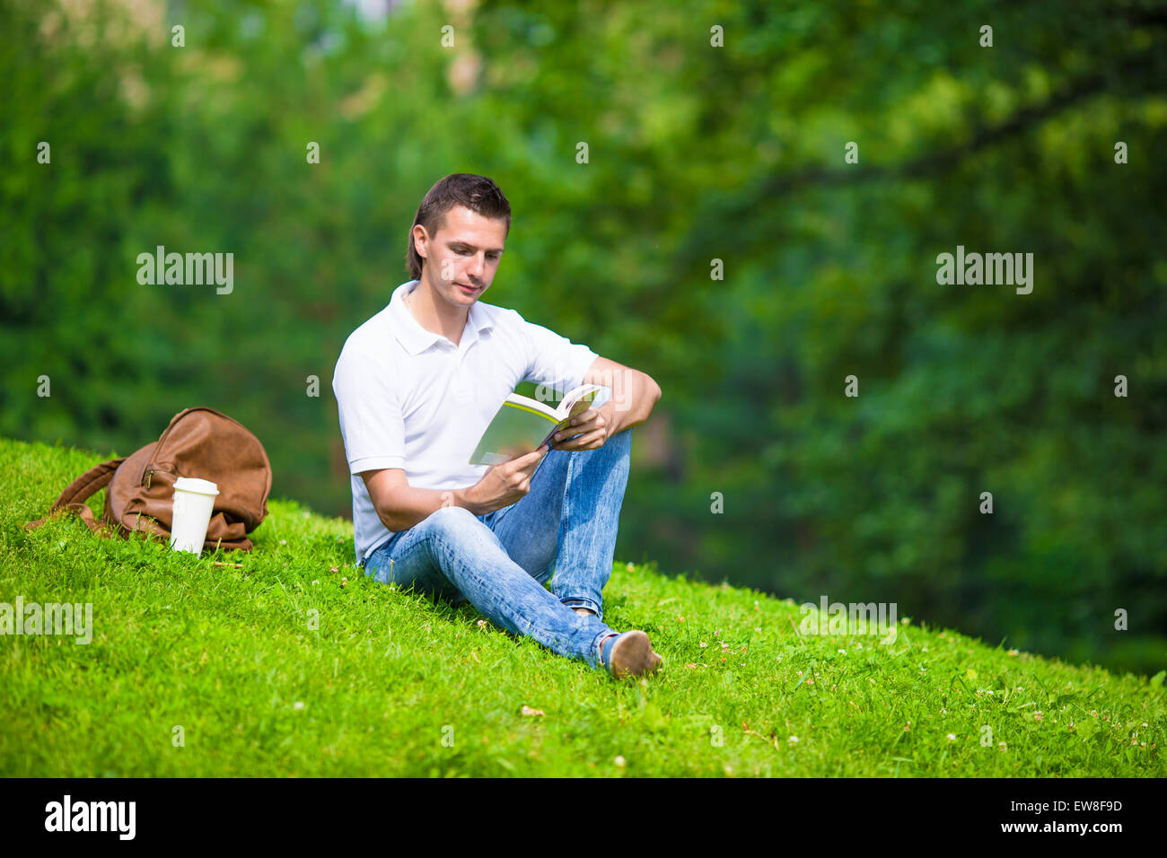 человек сидит на траве. человек под деревом. люди на газоне. парень сидит на траве. человек сидит на лугу.