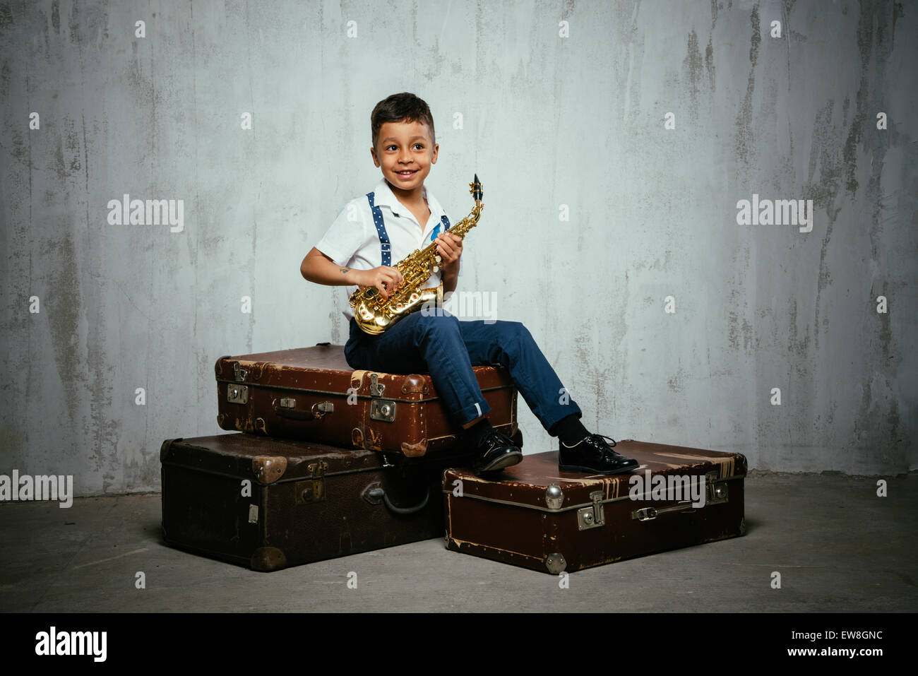 six years old boy sit with saxophone on retro suitcases Stock Photo Alamy
