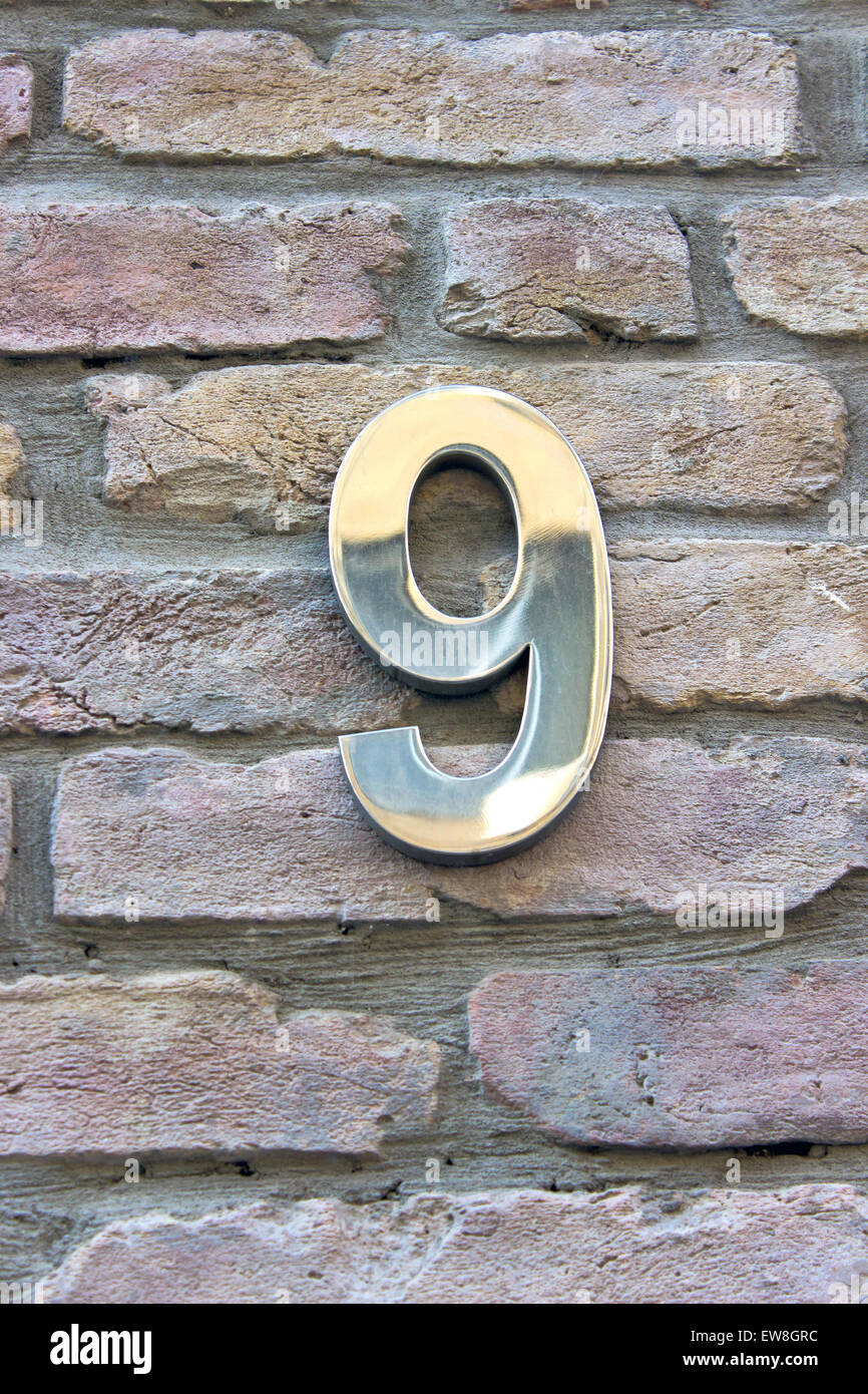 House number 9 zinc plate on brick wall Stock Photo