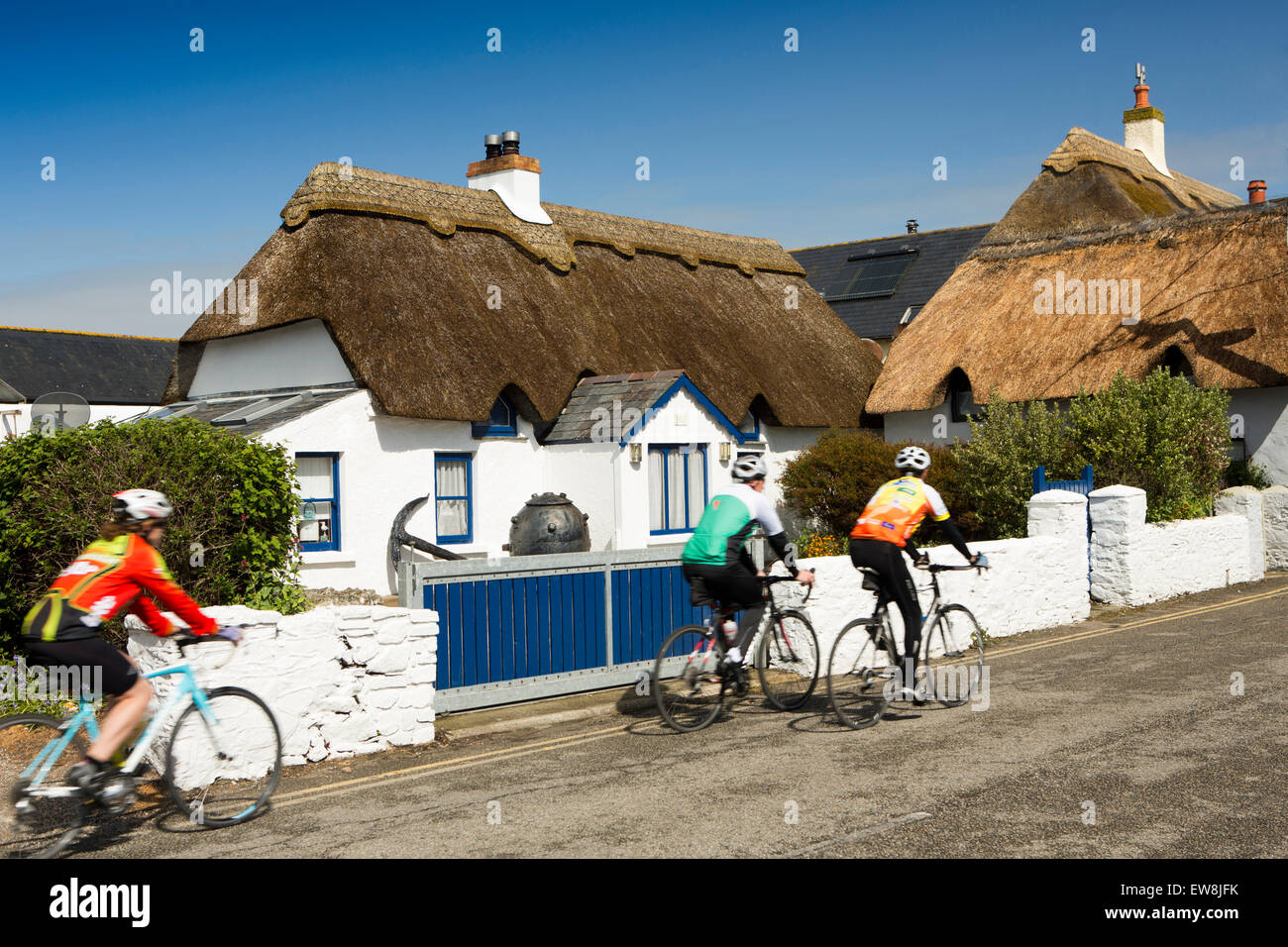 Ireland, Co Wexford, Kilmore Quay, cyclists passing idyllic thatched