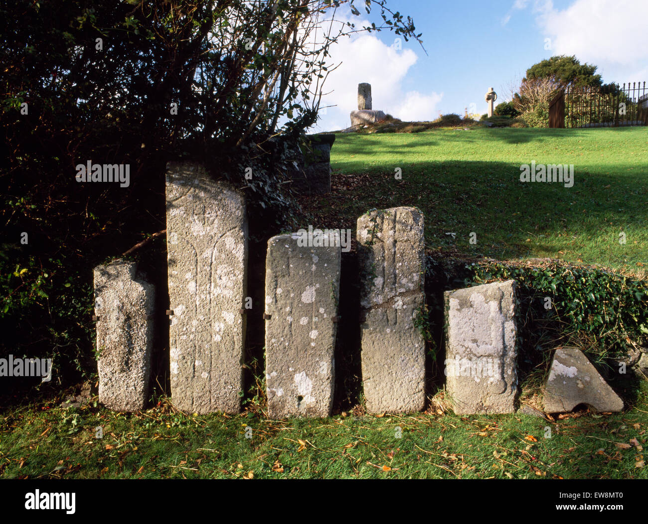 Early Medieval cross-marked gravestones in Llangaffo churchyard, Anglesey: cross-shaft & old church foundations on outcrop. Early monastic site. Stock Photo