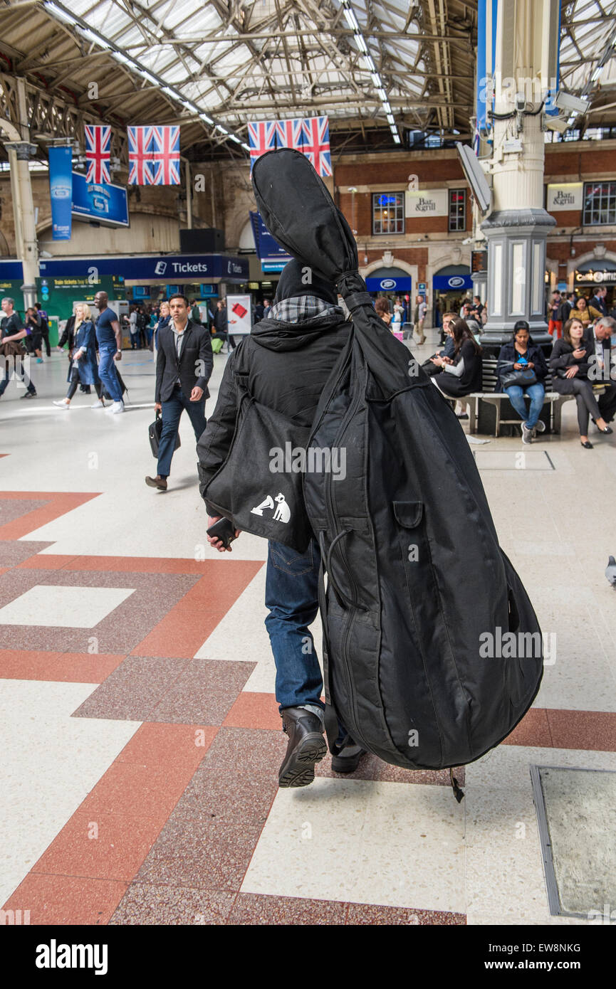 A man on a London street carrying a double bass in a protective