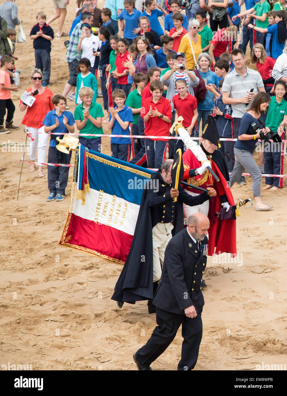 Broadstairs, Kent. 20th June, 2015. In commemoration of events after the Battle of Waterloo, a despatch is being carried from Belgium to London between 18 and 21 June. This morning, the despatch arrived at Broadstairs, Kent, carried by characters representing Major Henry Percy and Commander James White RN who brought the original despatch in 1815. The captured French Eagles are carried across te beach. Credit:  Paul Martin/Alamy Live News Stock Photo