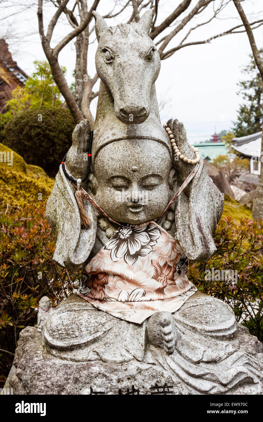 Japan, Miyajima. Daishoin temple. Small stone Jizo statue of a sitting