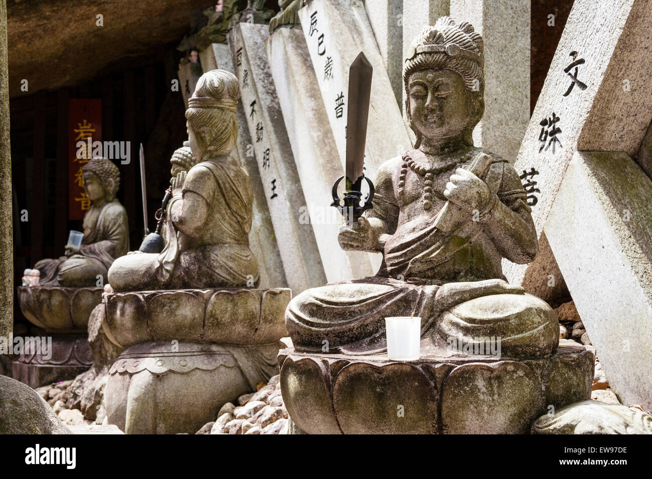 View along row of four Japanese stone statues of deities, gods, at the