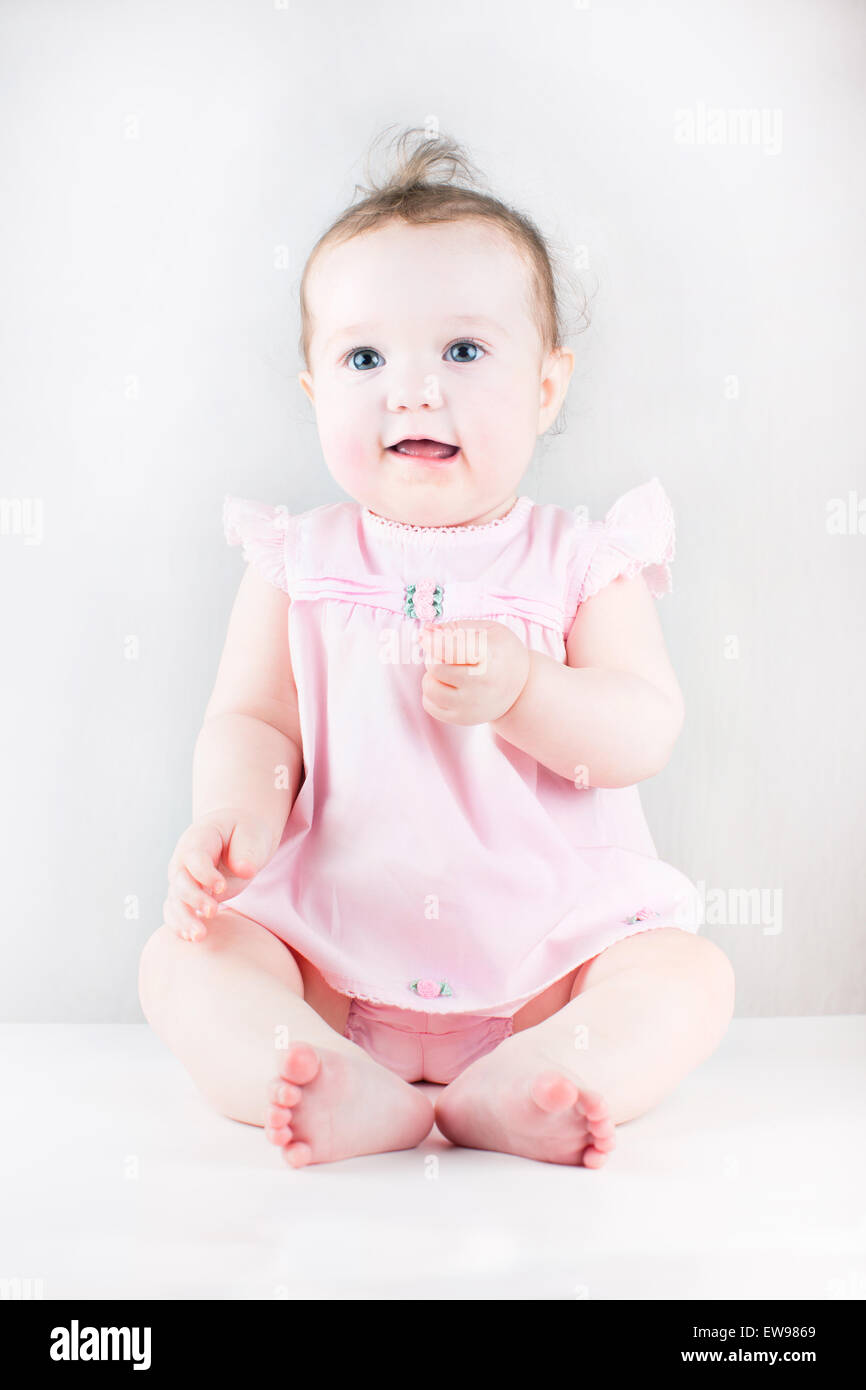 Cute baby girl sitting and wearing a pink dress Stock Photo - Alamy