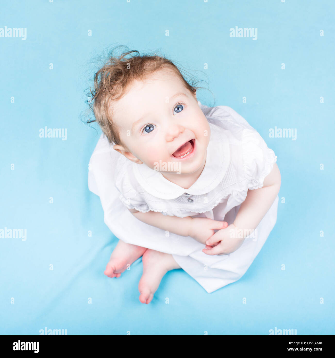 Beautiful little girl in a white dress on a blue blanket Stock Photo ...