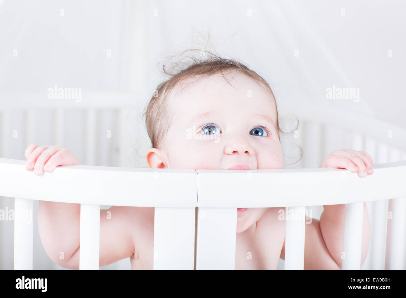 Funny little baby biting on a crib Stock Photo Alamy