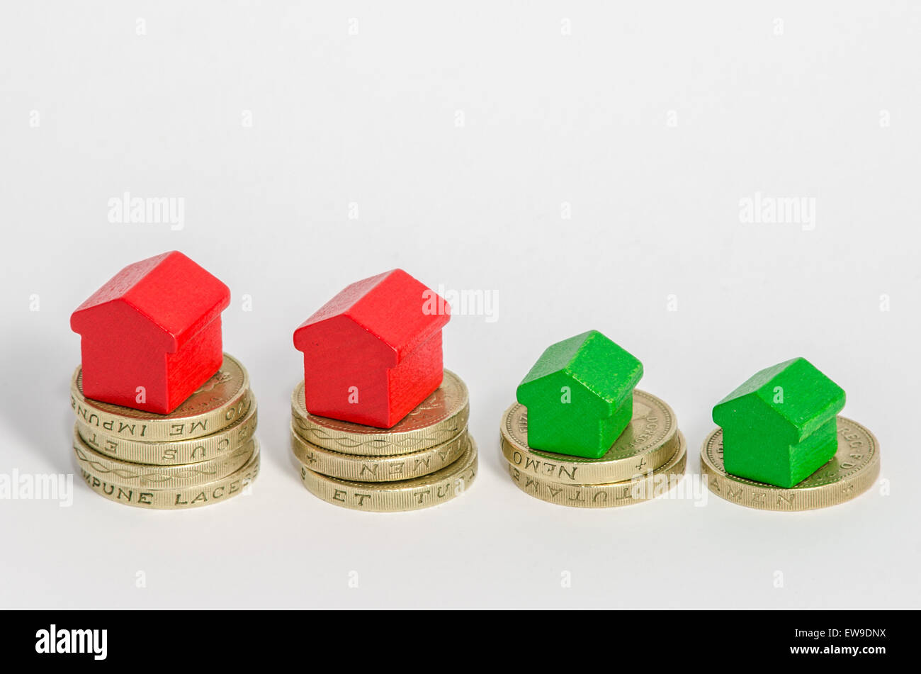 The largest stack or pile of cash has a main large red house and a secondary smaller green house. As the wealth of the stack get Stock Photo