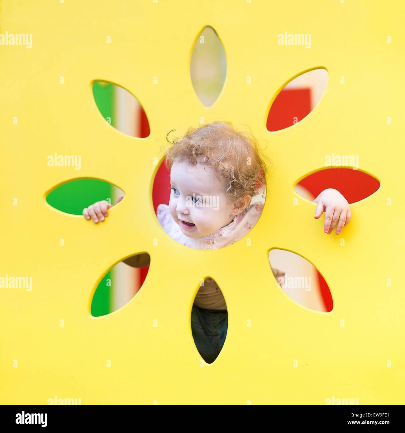 Funny curly baby girl playing hide and seek Stock Photo
