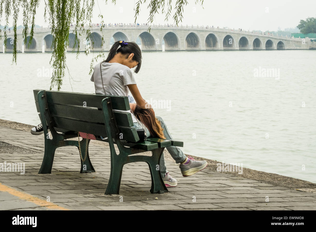 Two girls on a bench with the amazing 17 Arch Bridge in the background at Kunming Lake, Beijing, China Stock Photo