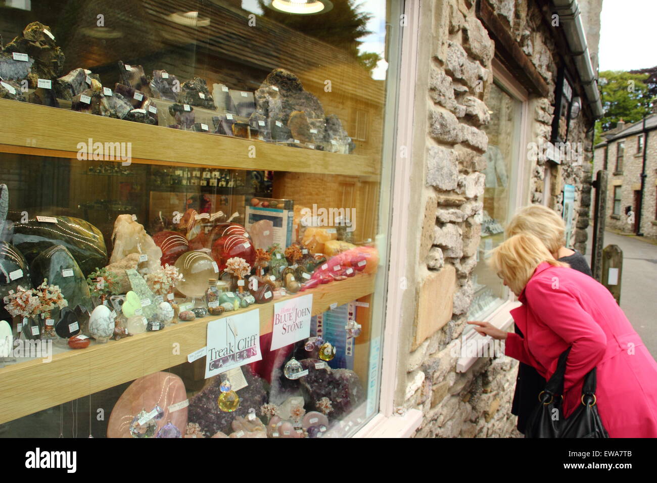 Two women peruse jewelery made with Blue John stone through a shop window in Castleton, Peak District, England UK Stock Photo