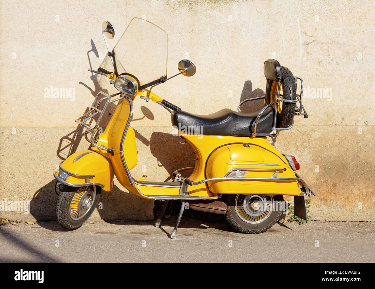 yellow retro motorcycle standing against wall Stock Photo
