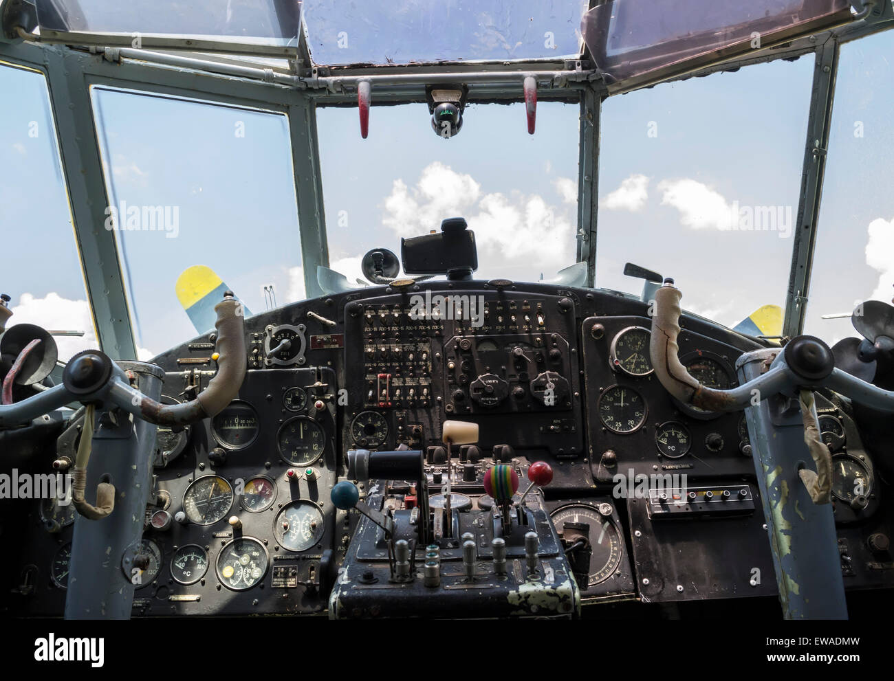 Vintage airplane cockpit interior with blue sky and white clouds in the background Stock Photo