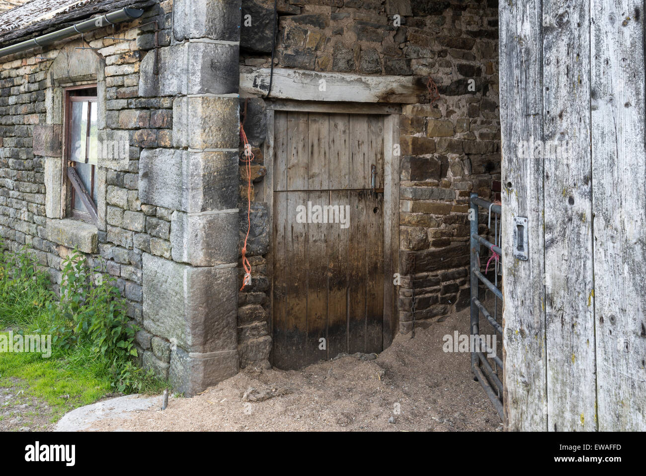 Old farm buildings in Northern England with stone walls and weathered wooden doors. Stock Photo