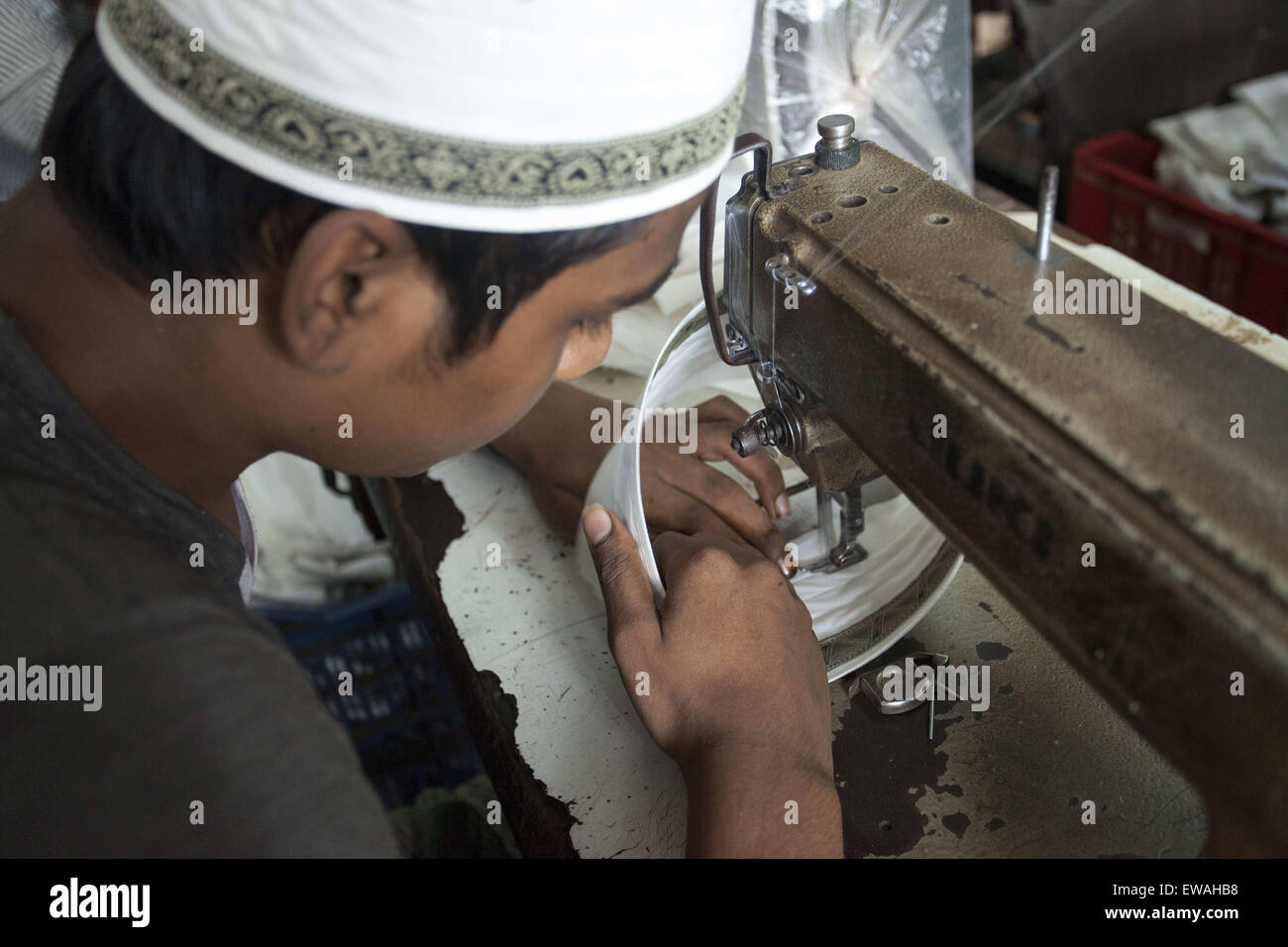 Dhaka, Bangladesh. 21st June, 2015. DHAKA, BANGLADESH 21st June : worker is busy at a factory in old Dhaka to making Tupi or prayer hats during holy Ramadan in Dhaka on 21st June 2015.There is a great demand for locally made prayer caps both at home and abroad. About 60 percent of all tupis manufactured are exported to countries like Pakistan, Saudi Arabia, India, and other muslim countries. The rest is supplied to the domestic market.The livelihood of nearly three thousand craftsmen who make prayer caps (tupi) hang in the balance as around a hundred tupi factories in the old part of the cit Stock Photo