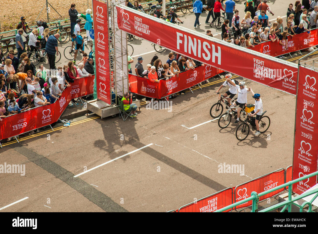 Brighton, UK. 21st June, 2015. Cyclists pass the finish line holding hands. Crowd of onlookers cheers. Credit:  Slawek Staszczuk/Alamy Live News Stock Photo
