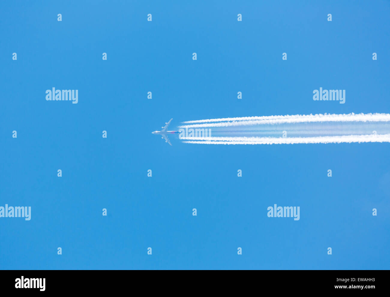 A plane flying on a clear blue sky with vapor trail Stock Photo