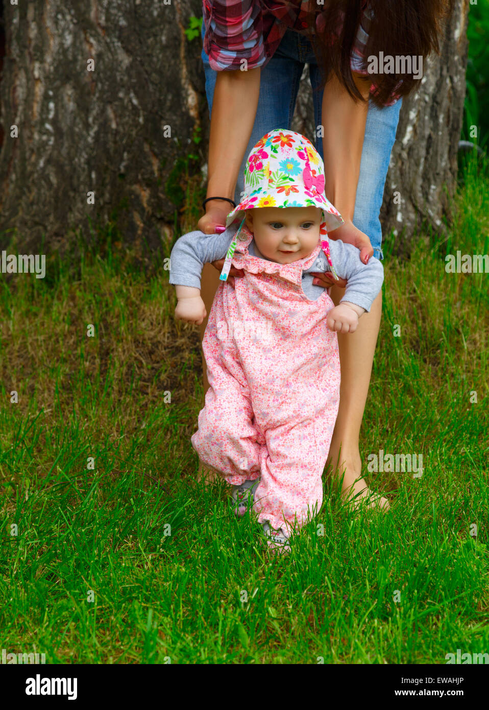Little girl makes the first steps with the help of mom Stock Photo