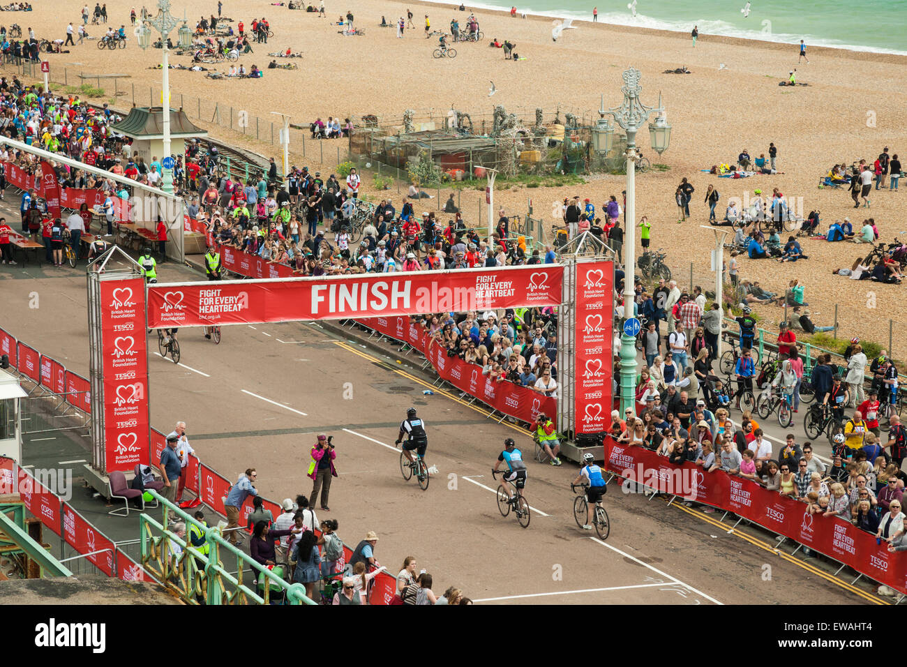 Brighton, UK. 21st June, 2015. Cyclists pass the finish line. Crowd of onlookers cheers. Brighton beach in the background. Credit:  Slawek Staszczuk/Alamy Live News Stock Photo