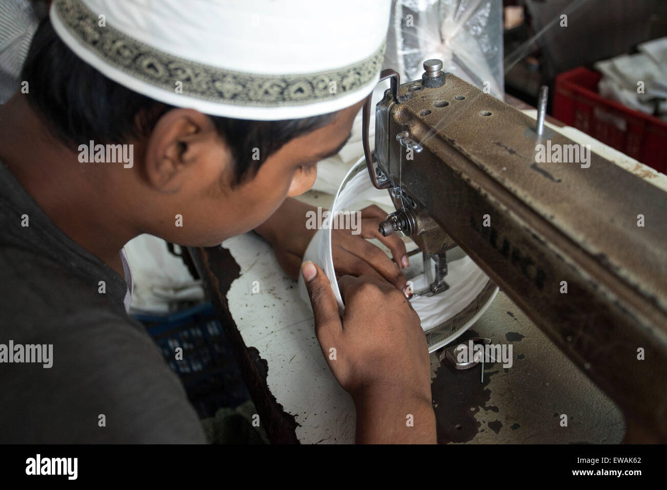 DHAKA, BANGLADESH 21st June : worker is busy at a factory in old Dhaka to making Tupi or prayer hats during holy Ramadan in Dhaka on 21st June 2015. There is a great demand for locally made prayer caps both at home and abroad. About 60 percent of all tupis manufactured are exported to countries like Pakistan, Saudi Arabia, India, and other muslim countries. The rest is supplied to the domestic market.The livelihood of nearly three thousand craftsmen who make prayer caps (tupi) hang in the balance as around a hundred tupi factories in the old part of the city Dhaka. Stock Photo