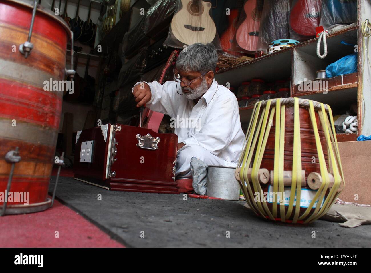 Lahore. 21st June, 2015. A Pakistani man repairs musical instruments at