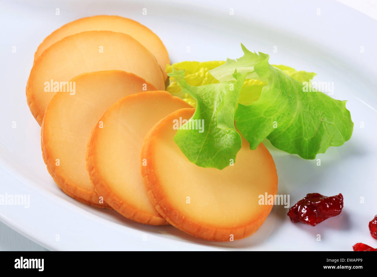 Slices of smoked cheese on plate Stock Photo