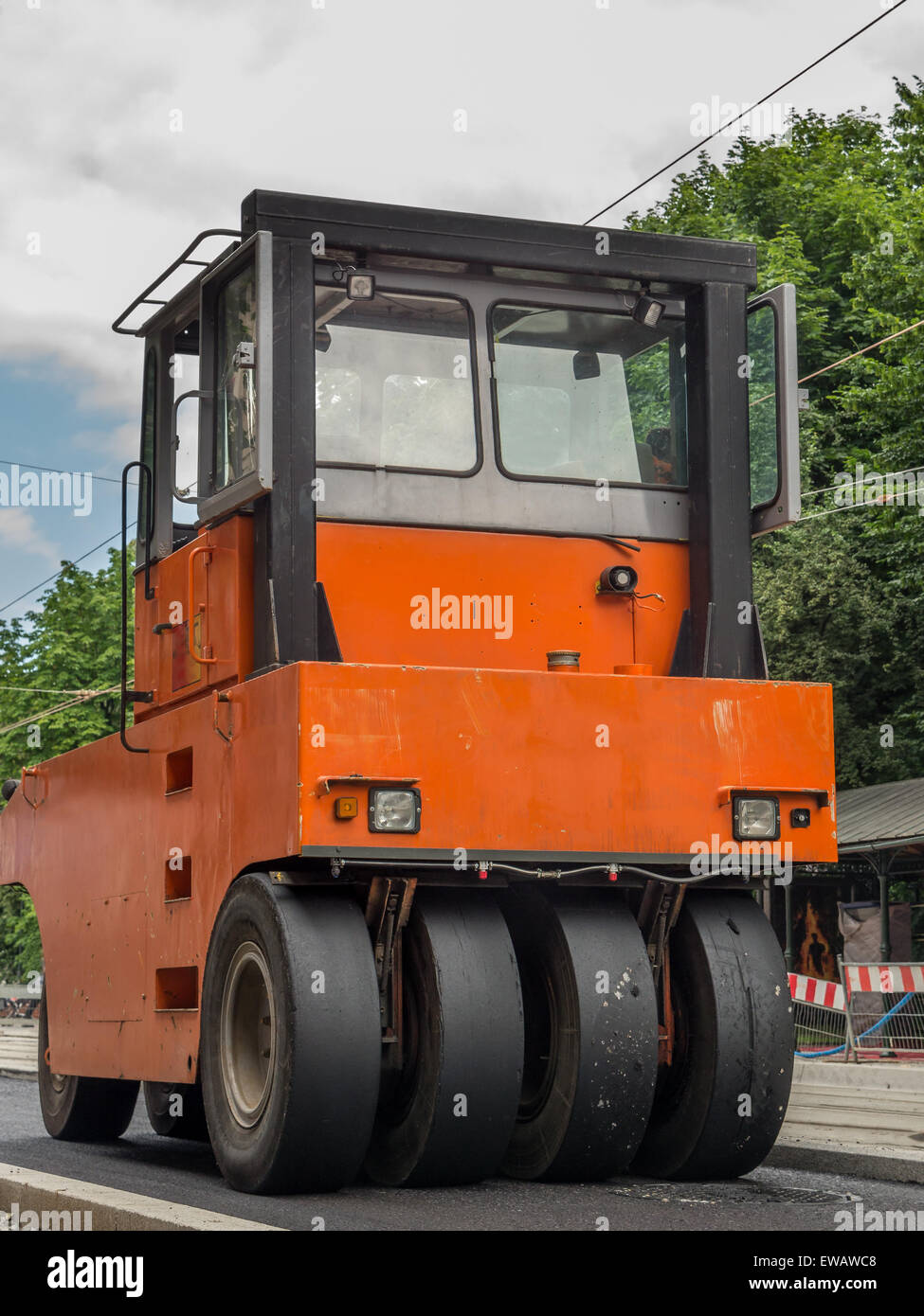 Orange road roller smoothing out fresh asphalt layer Stock Photo