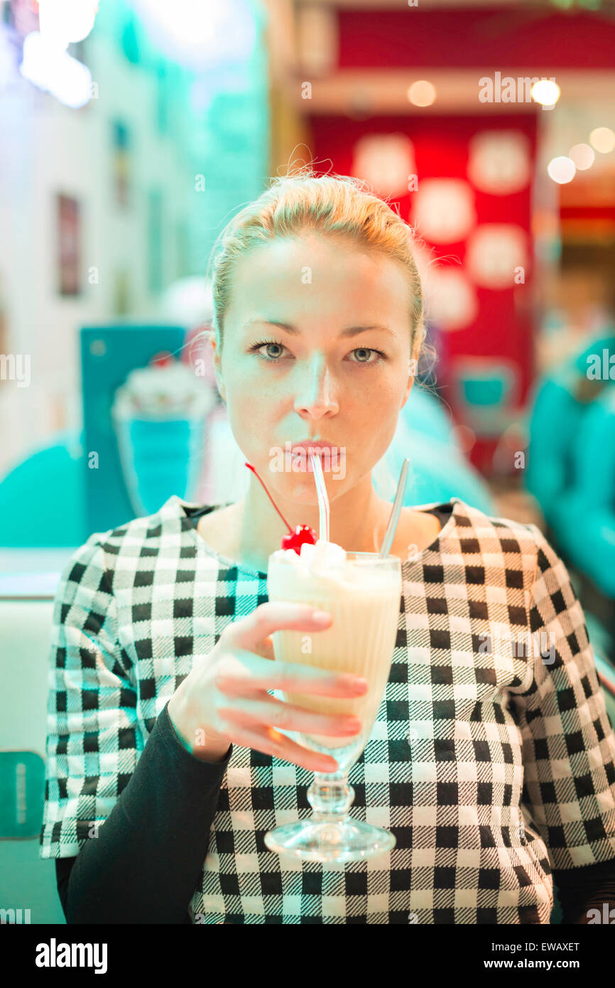 Woman drinking milk shake in diner. Stock Photo