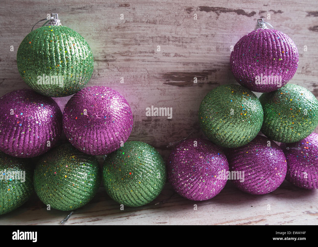 Pink and green christmas balls in a stack over wooden background in a studio shot Stock Photo
