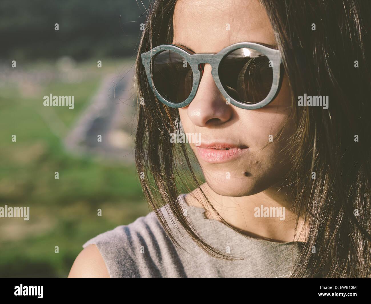Brunette woman with sunglasses in a close up portrait outdoors Stock Photo