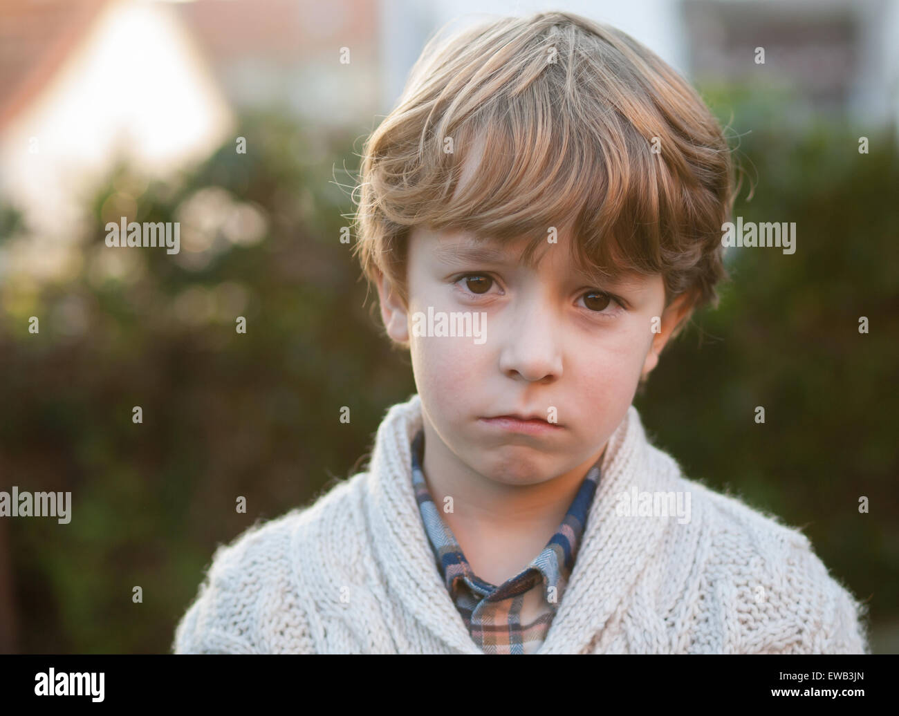 Sad little boy looking at camera outdoors Stock Photo