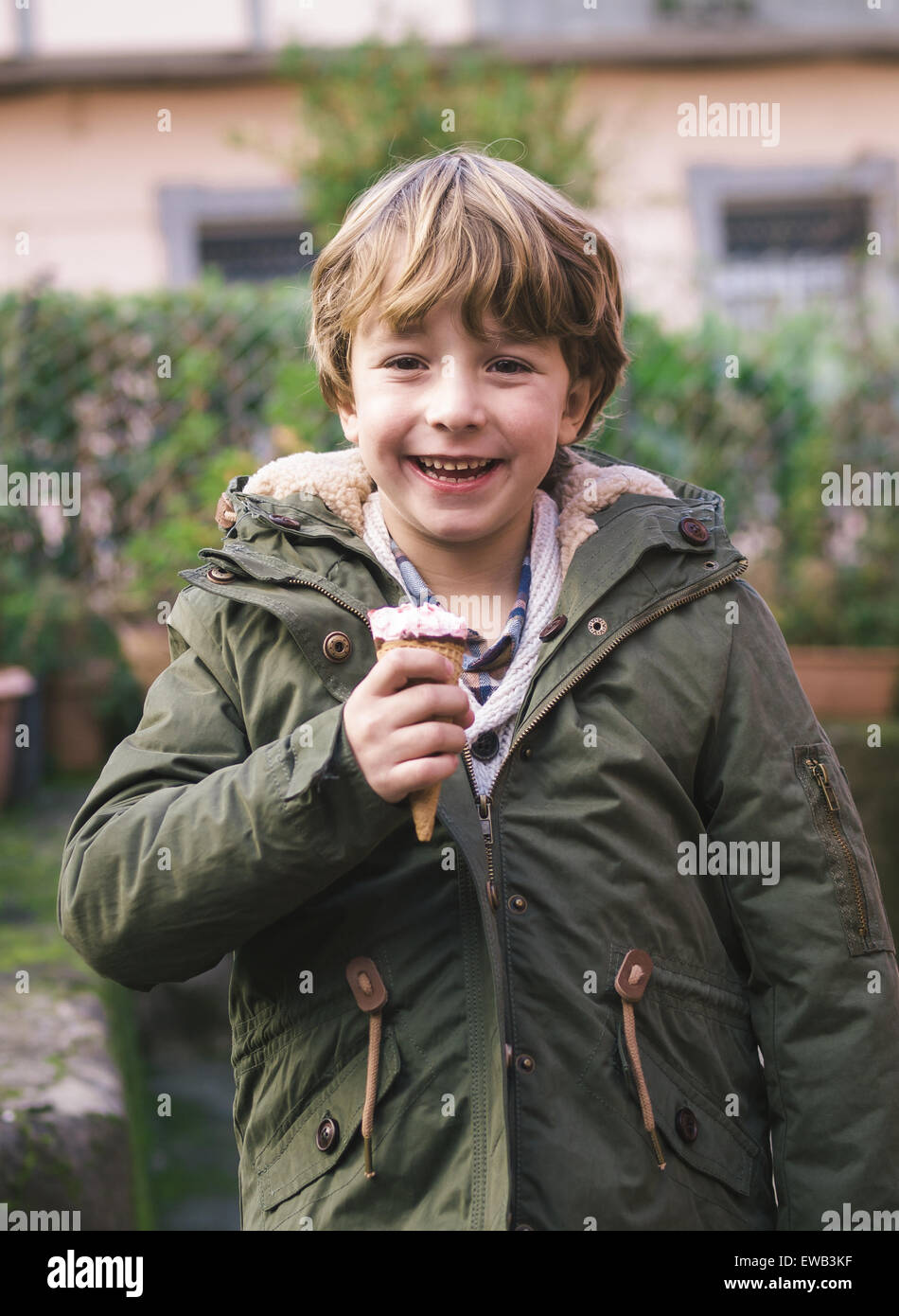 Blonde boy with an ice crean in winter. The boy is smiling. Stock Photo