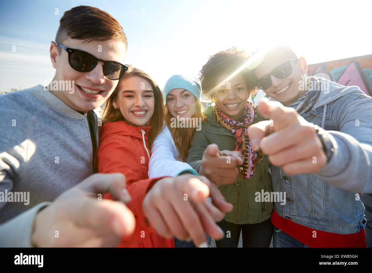 happy teenage friends pointing fingers on street Stock Photo