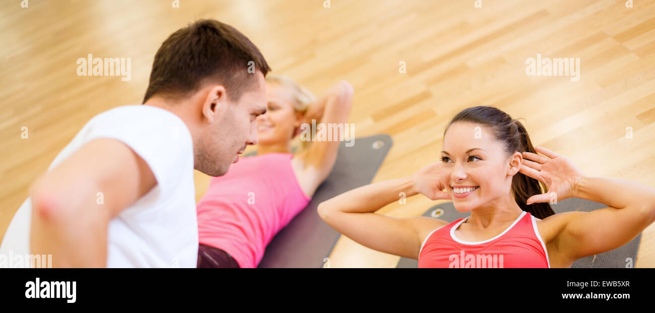 group of smiling women doing sit ups in the gym Stock Photo