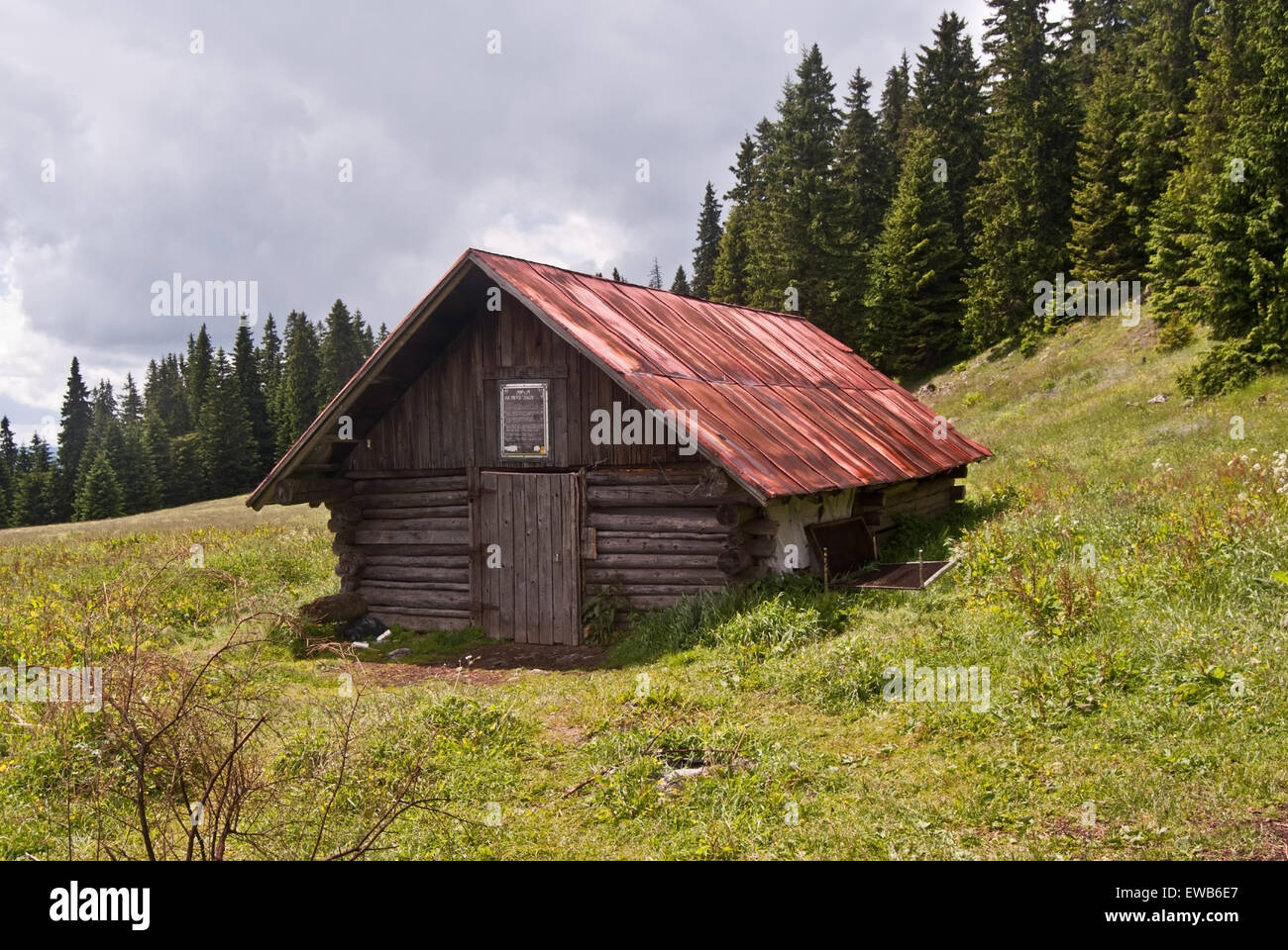 wooden hut on Stredna polana mountain meadow with pathway and trees on the background bellow Velky Choc hill in Chocske vrchy mountains in Slovakia Stock Photo