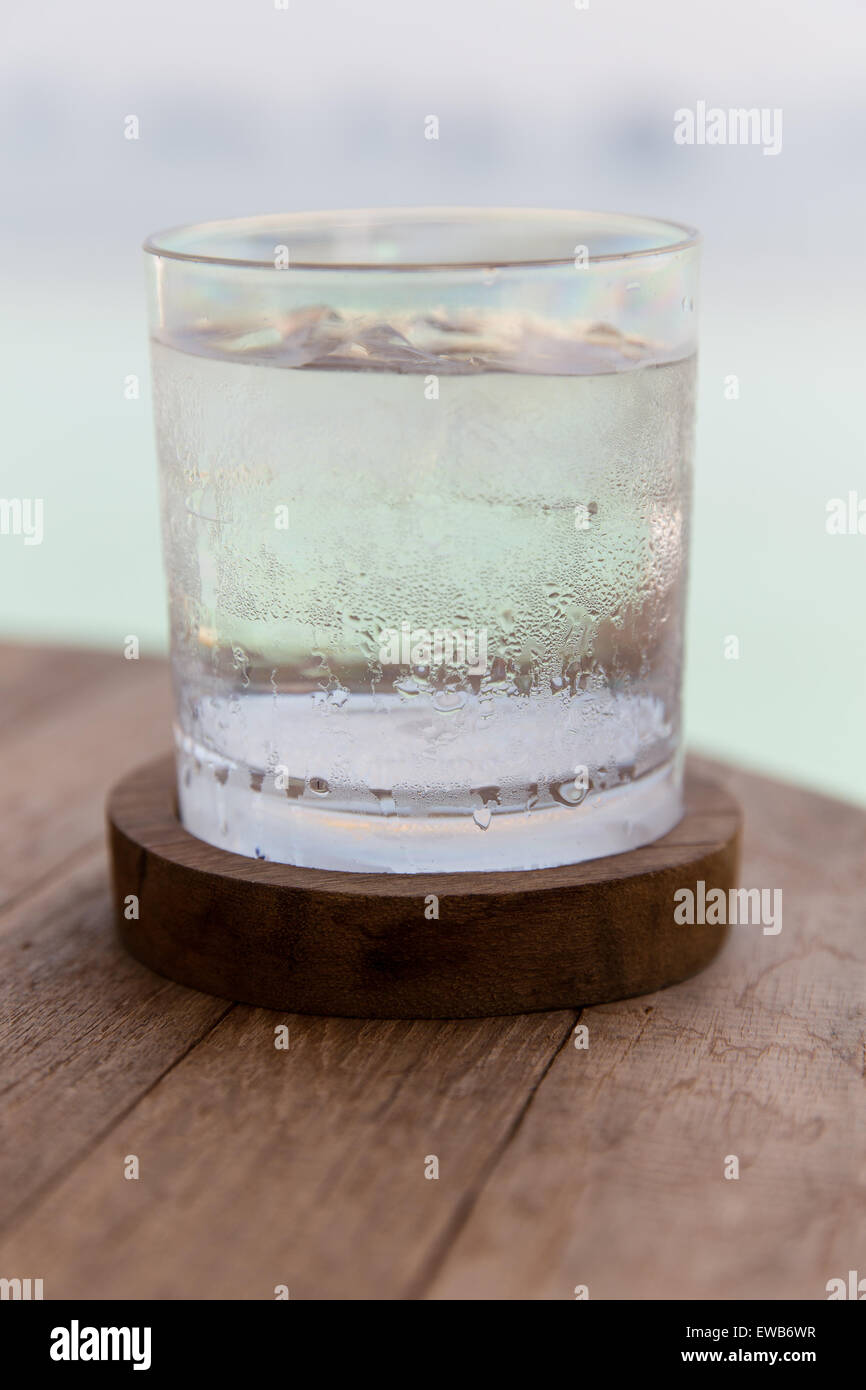 glass of water with ice cubes on table at beach Stock Photo