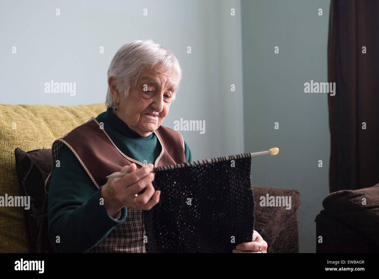 Elderly woman knitting at home. Woman is focus in her activity. Stock Photo