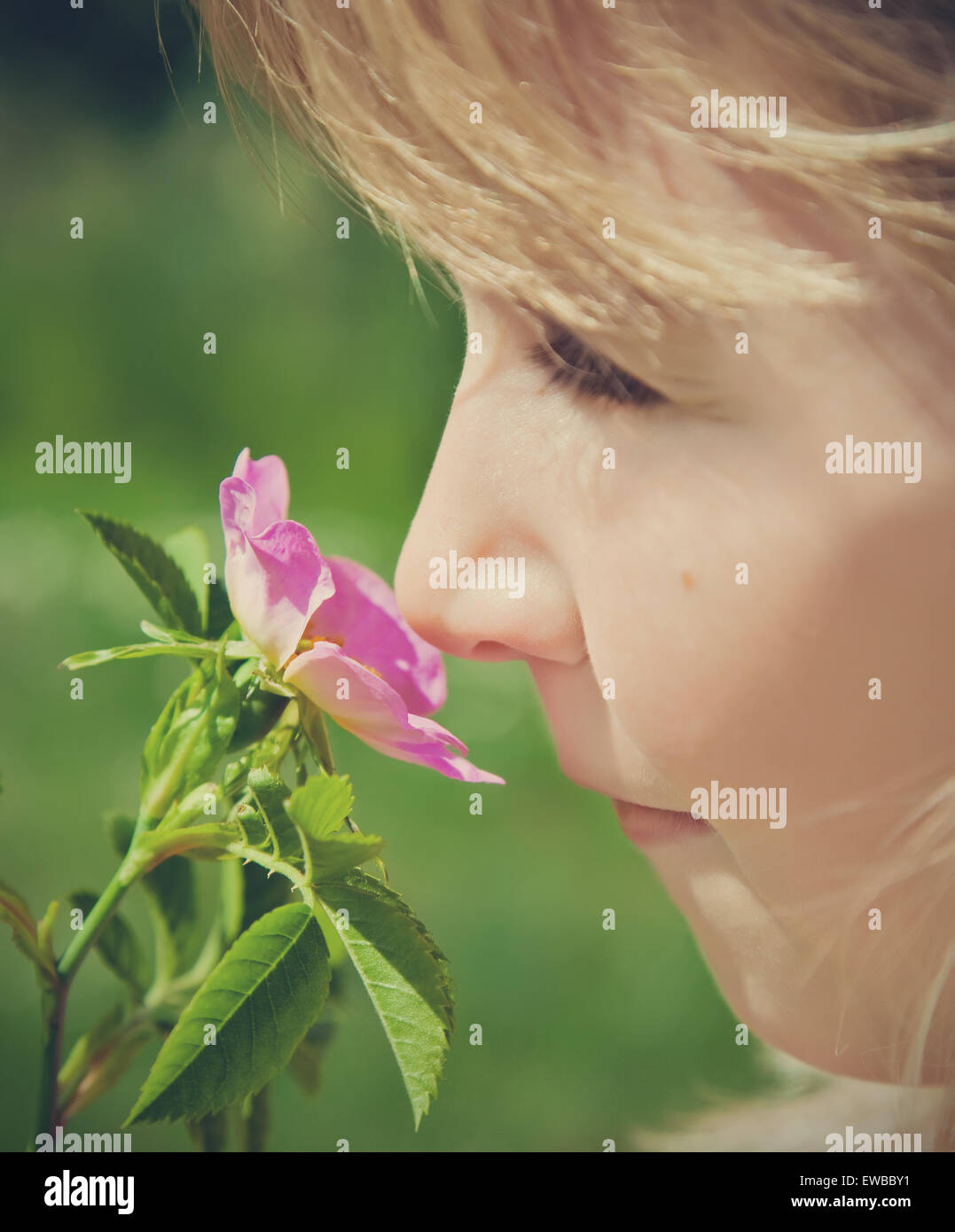 young girl smelling pink blossom Stock Photo
