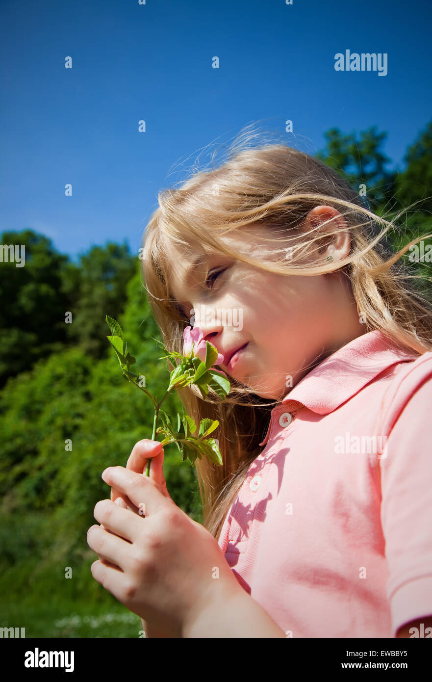 young girl smelling pink blossom Stock Photo