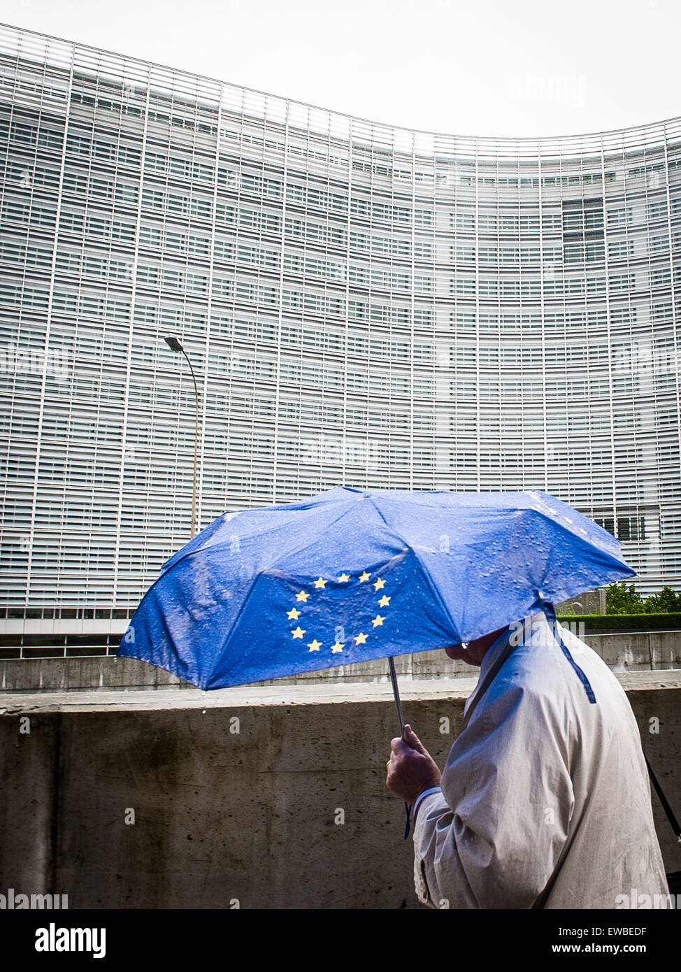 Brussels, Bxl, Belgium. 22nd June, 2015. Pedestrian under umbrella with European Union flag is walking along European Commission headquarters building in Brussels, Belgium on 22.06.2015 Heads of Eurozone state will geather for emergency summit on Greek debt today in EU headquarters by Wiktor Dabkowski © Wiktor Dabkowski/ZUMA Wire/Alamy Live News Stock Photo