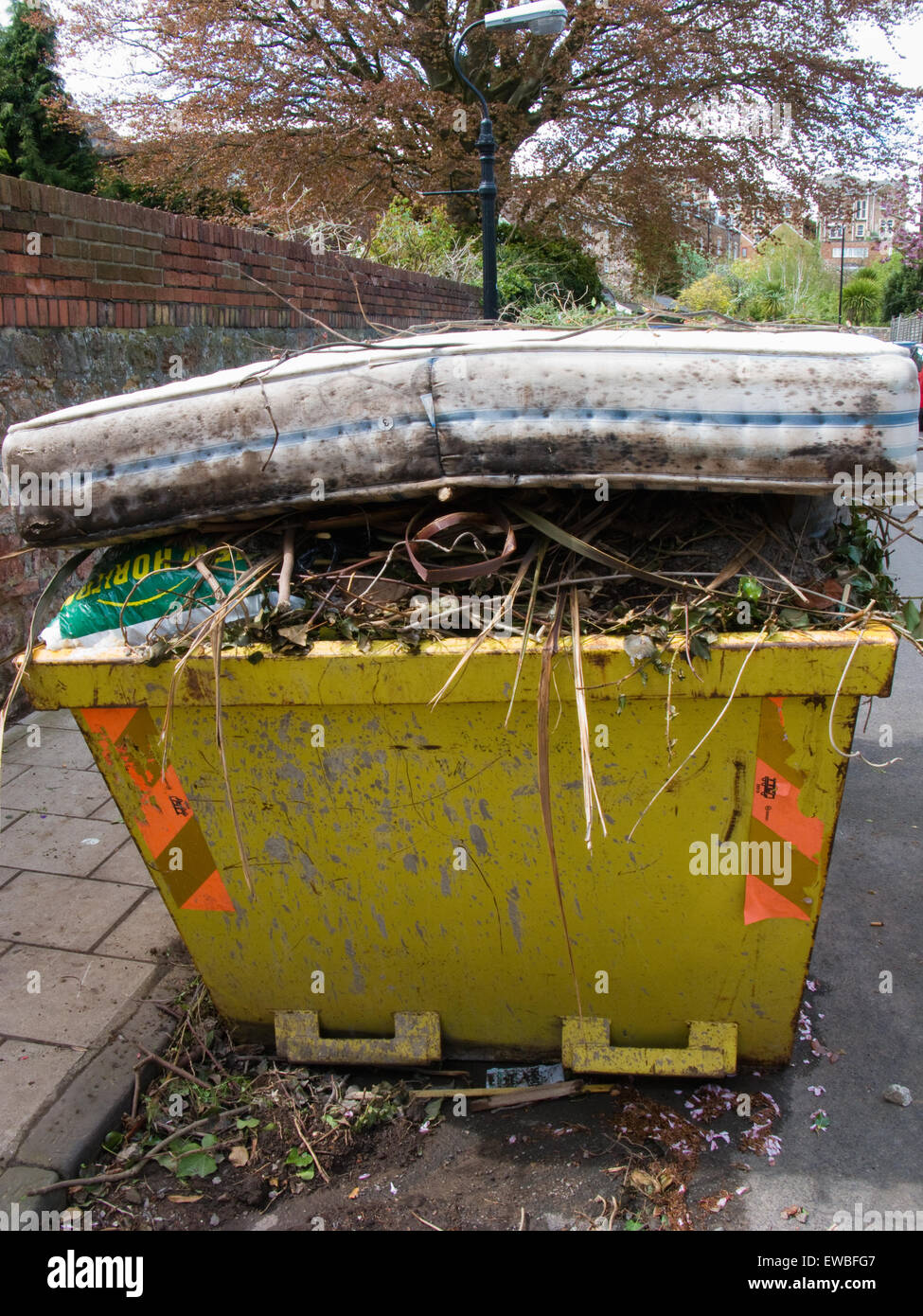 Rubbish skip overflowing on street with old mattress Stock Photo Alamy