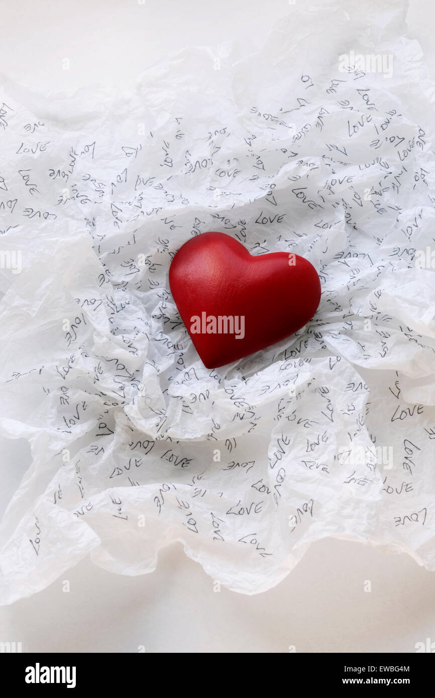 Red heart on white tissue paper inscribed with the word Love Stock Photo