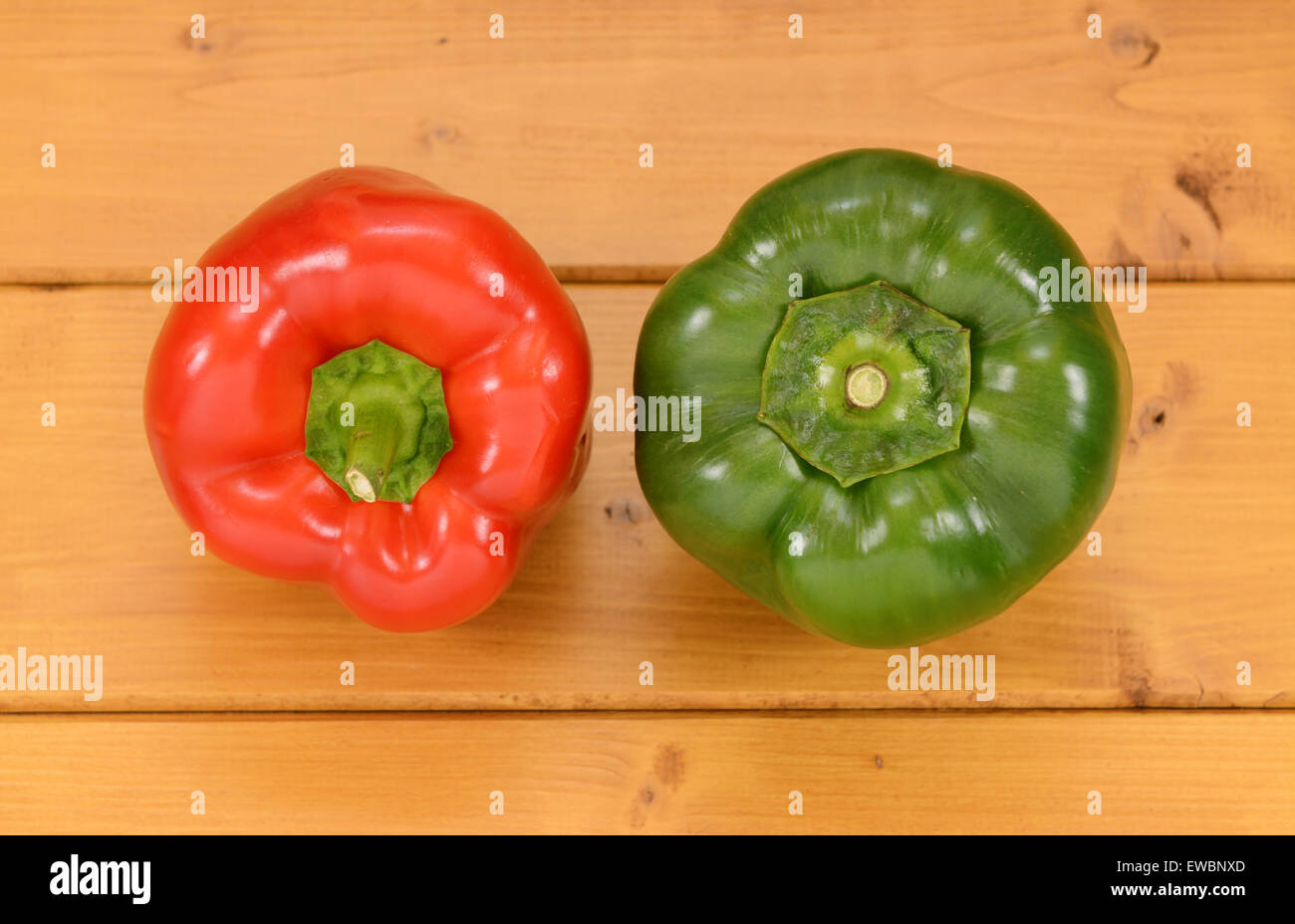 Red And Green Capsicum Peppers On A Wooden Kitchen Table Stock Photo Red and green capsicum peppers on a wooden kitchen table stock photo