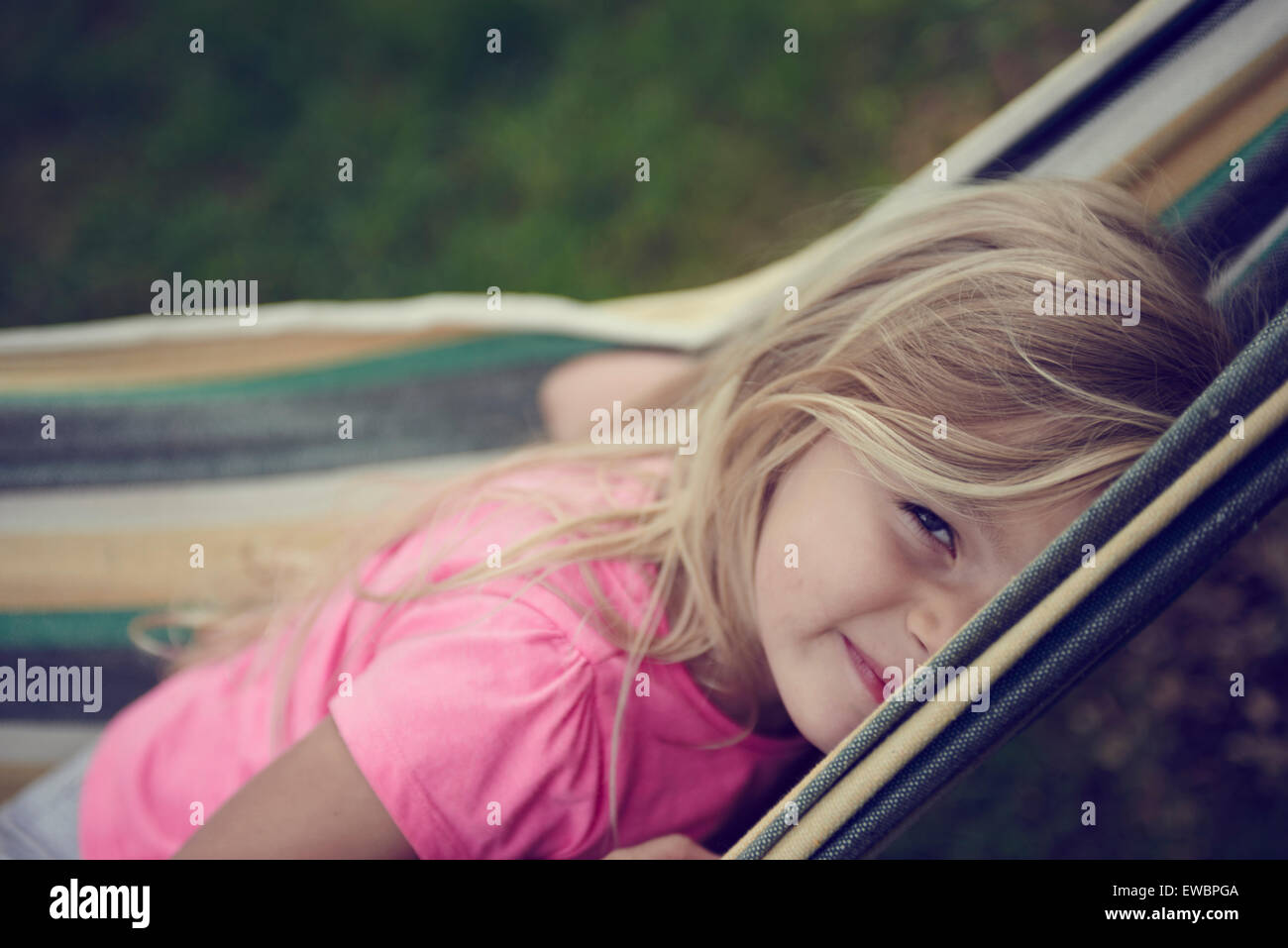 Child Blond Girl Lying in Hammock, summertime Stock Photo