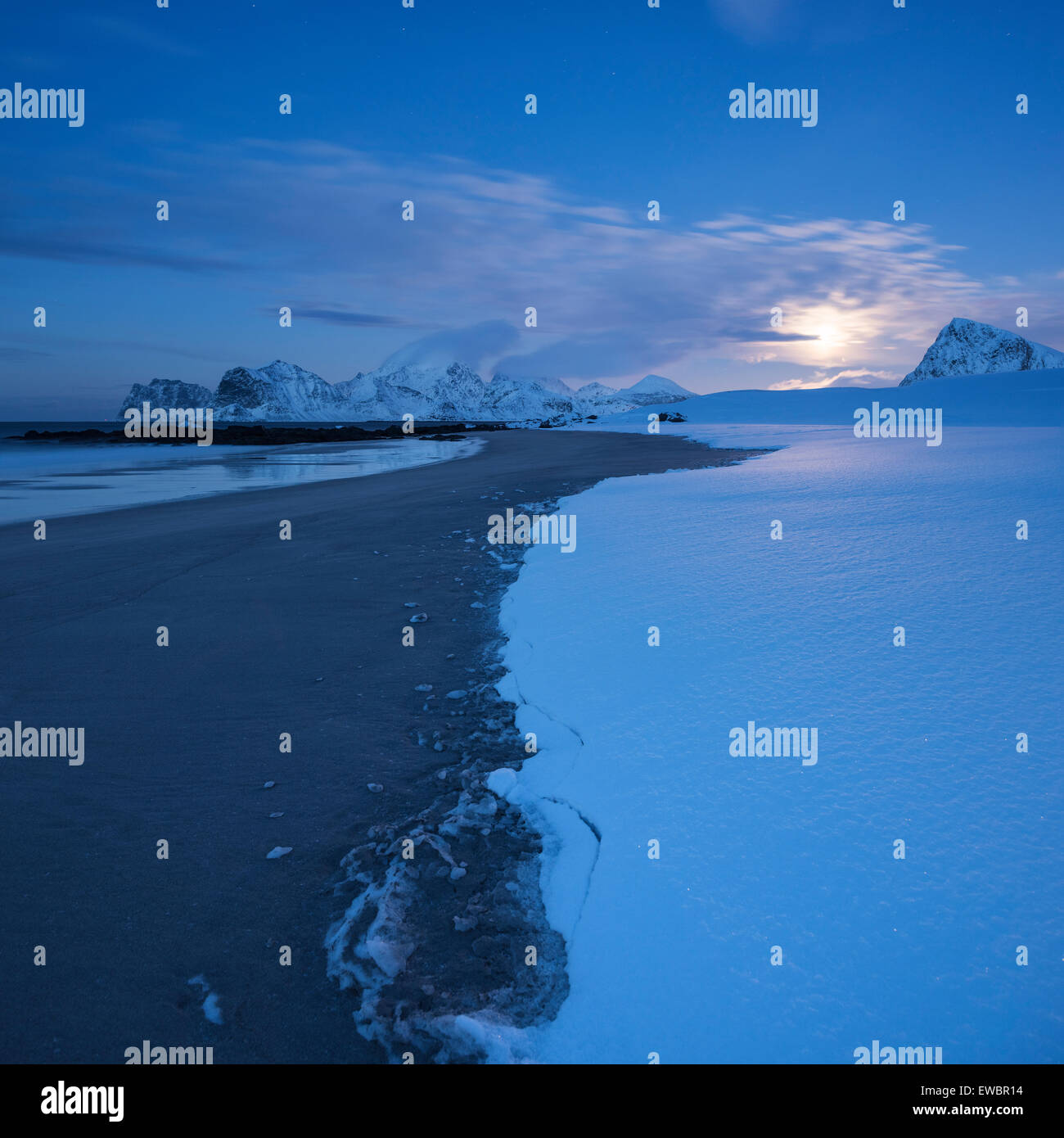 Moon rises over snow covered Storsandnes beach in winter, Flakstadøy, Lofoten Islands, Norway Stock Photo